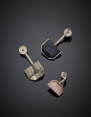 trois bijoux en argent et en or posés sur un fond noir