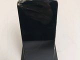 a black cell phone sitting on a stand on a white surface