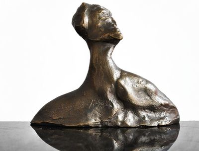 bronze sculpture of a woman sitting on top of a glass table