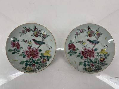 two plates with flowers and birds on them sitting on a table