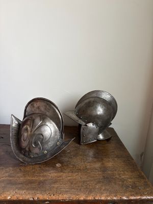 deux casques métalliques posés sur une table en bois dans une pièce