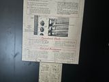 a newspaper on the door of a black refrigerator