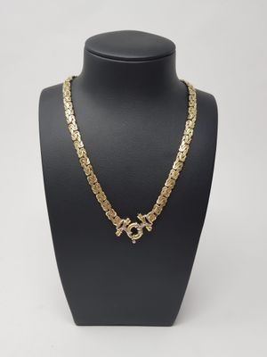 a gold chain necklace with a cross charm on a mannequin