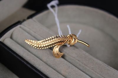 une broche en forme d'oiseau en or posée sur une bague