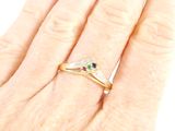 an image of a woman ' s hand with a diamond and emerald ring on it