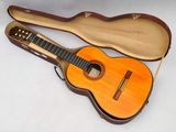 une photo d'une guitare acoustique dans son étui, posée sur une surface blanche