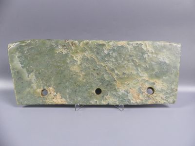 bloc de marbre vert percé de trous sur une surface blanche