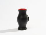 a black vase with a red top on a white surface