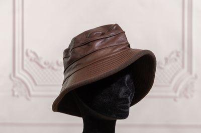 brown leather bucket hat on mannequin head in front of a white wall