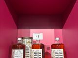 trois bouteilles d'alcool posées sur une étagère, dans une boîte rose