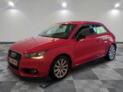 L'Audi rouge est garée dans une grande pièce au sol carrelé.