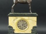 statue d'un cheval posée sur un socle en marbre, avec une horloge au centre