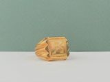 une photo d'une bague en or posée sur une table blanche