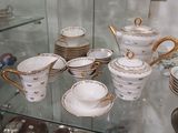 une vitrine en verre contenant de nombreux types de tasses à thé et de soucoupes
