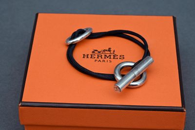 an orange box with a silver bracelet and a black cord