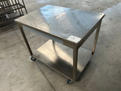 une table en acier inoxydable montée sur roulettes dans un entrepôt