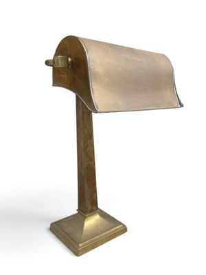 an image of a brass desk lamp with a roll of paper on it