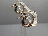 pair of gold tone hoop earrings on clear acrylic stand