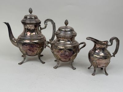 deux théières en argent et une cafetière posées sur une table