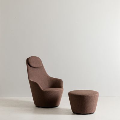 une photo représentant une chaise et un pouf dans une pièce blanche