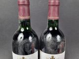 two bottles of red wine sitting next to each other on a table