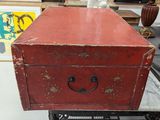 an old red chest sitting on a table in a room