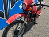 une moto rouge garée devant un panneau bleu et blanc