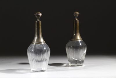 une paire de vases en argent et en verre posés sur une table, sur fond noir