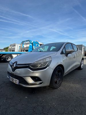 La voiture argentée est garée sur le parking, avec d'autres voitures en arrière-plan.