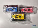 three toy cars in plastic bags on a white surface