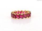 a close up of a gold ring with pink stones on a white surface