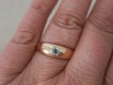 la main d'une personne tenant une bague en or sertie d'un diamant