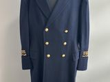 un manteau bleu à boutons dorés posé sur un présentoir pour mannequin