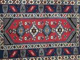 a red and blue rug with a diamond design on it