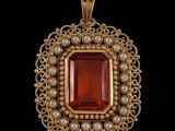 un pendentif en or orné d'une pierre rouge entourée de perles