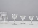 five wine glasses and a pitcher sitting on a table