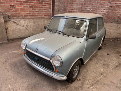 a small blue car parked in front of a brick wall