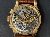 a close up of a watch on a black surface with a brown strap