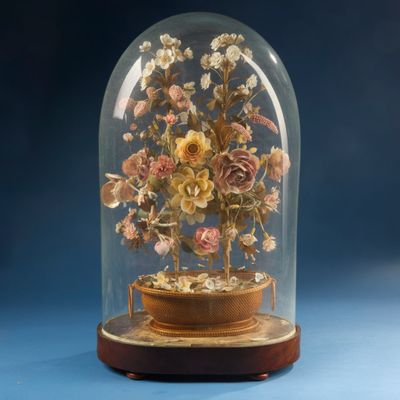 a glass dome with flowers inside of it on a blue surface