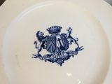 une assiette bleue et blanche sur laquelle figure un blason