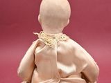 a small doll that is sitting on a pink surface