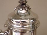 a silver coffee pot with a flower on top of it