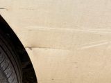 a cat sitting on the side of a car with its paw on the tire