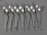 six cuillères en argent sont alignées sur une table