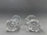 une paire de vases en verre transparent posés sur une surface grise, avec un fond gris
