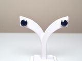 une paire de boucles d'oreilles à clous en saphir bleu, présentées sur un socle blanc
