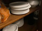 many plates and bowls on the shelves in the kitchen