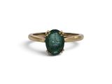 un gros plan d'une bague en or sertie d'une émeraude verte