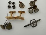 several pairs of cufflinks and a pair of cufflinks on a white surface