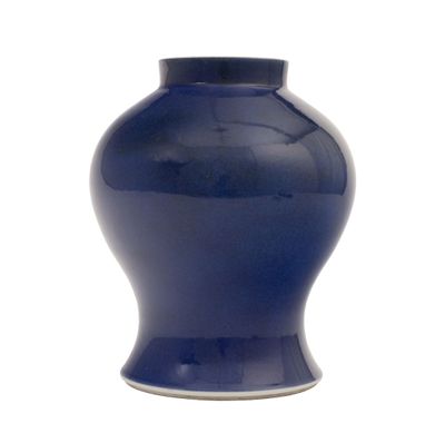 un vase bleu posé sur une surface blanche